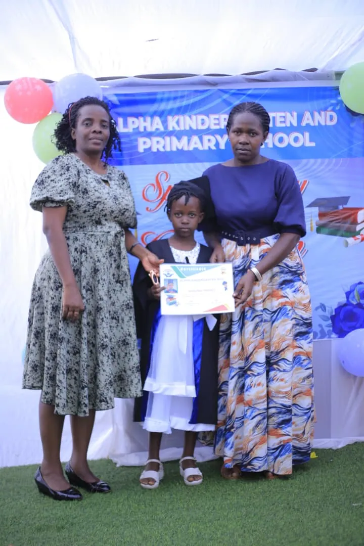 A child holding a certificate beside two adults at a school event.