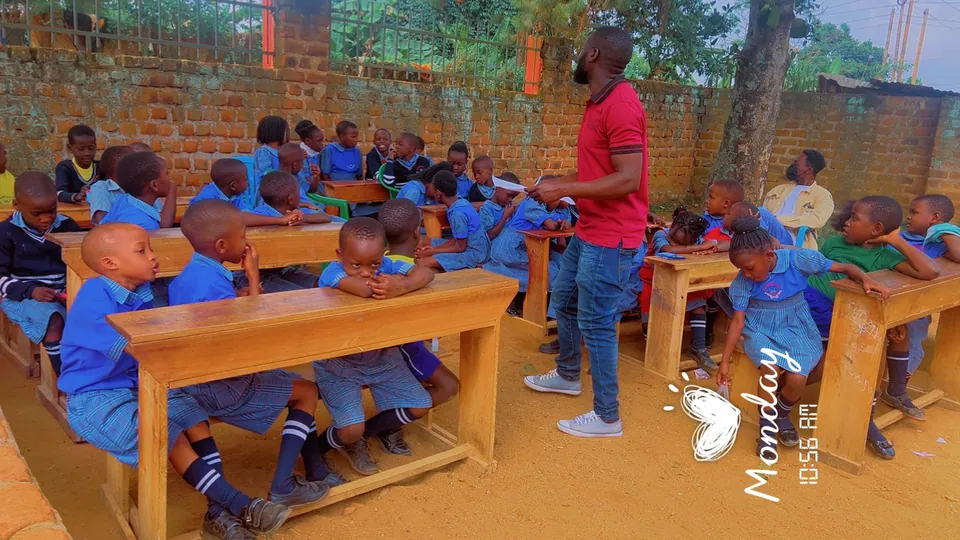 Children seated at classroom desks with an adult nearby.