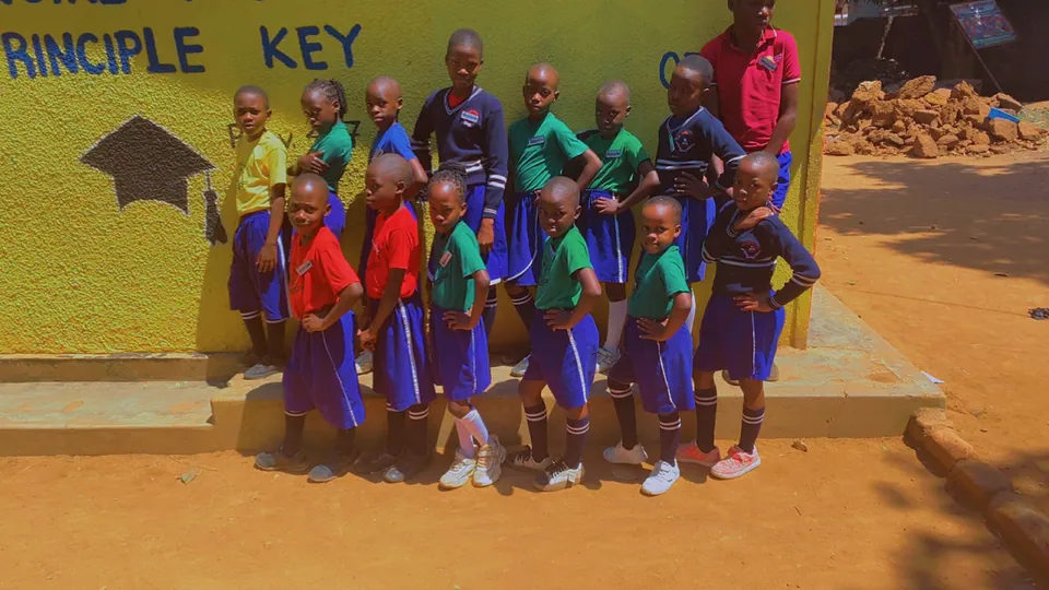 Children and adults gathered near the school motto wall.